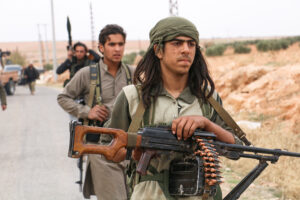 People With Rifles And Ammunition Walking On Road